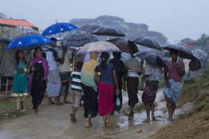 Rohingya Refugees move through a camp in the rain