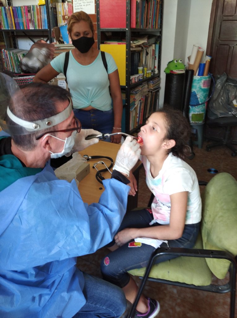 Medical team examines orphan girl's tonsils.