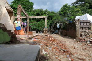 A girl in Oaxaca stands beside her destroyed home