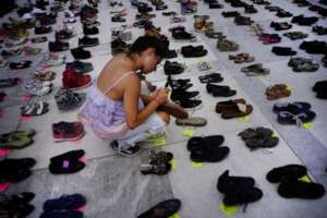 A woman places a shoe in memory of those died