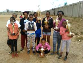 Girls holding trophies won with caregiver