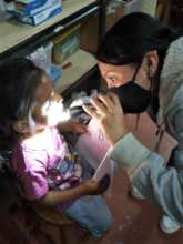 Ana checks the condition of a child's teeth.