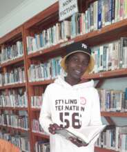 Tumaini is reading a story book at Jifundishe