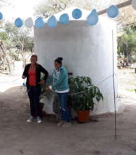 Two women cut the ribbon on their new water source