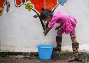 Girl takes rainwater from the school system