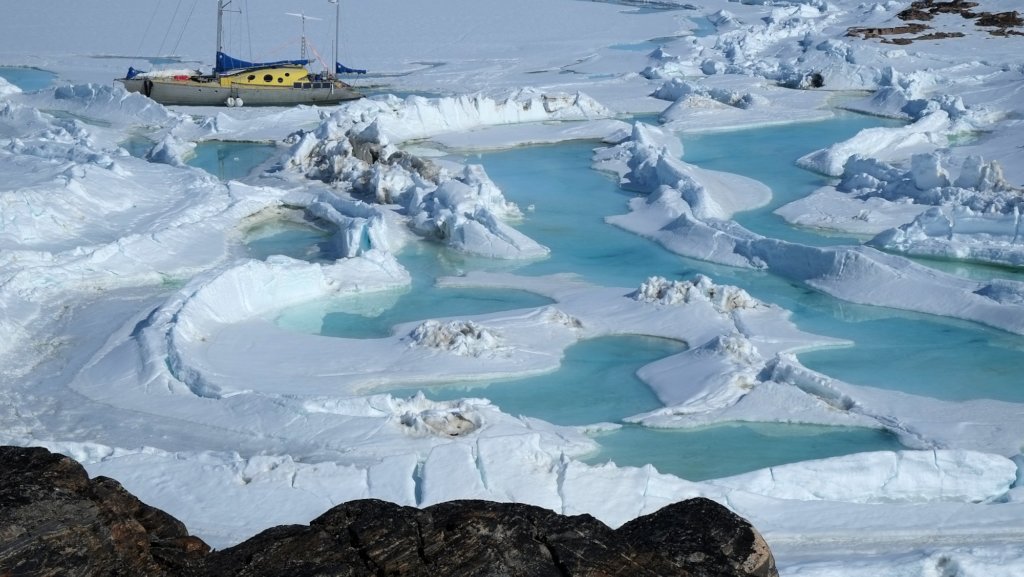 A boat on a frozen lake or ocean, near some blue pools