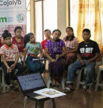 Dolores sits in the front row in a green guipil