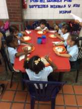 Kindergarten students eating lunch with cutlery