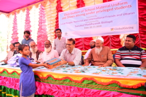 A student receiving shoes from Uttaran's director