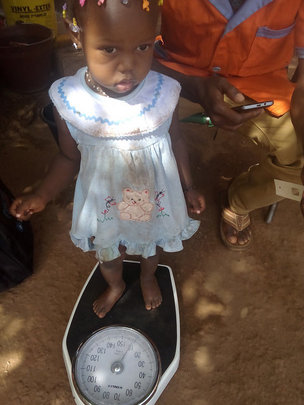 CHW weighing a child