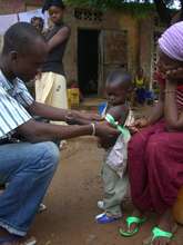 A community health worker measures a child's arm