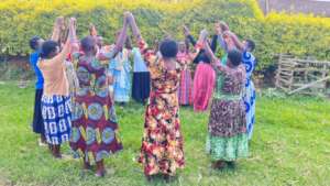 Women stand hand in hand in a circle.