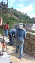 A volunteer carries bricks to the future home site