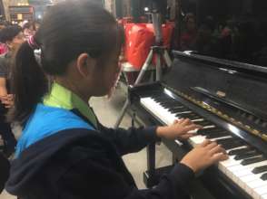 A little girl in children's home playing piano
