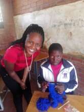 Mentor Tinaye with mentee crocheting