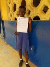 Janet in school holding her terminal report card.