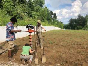 Interns using the hydraulic post hole digger