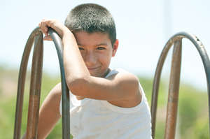 Boy sitting on rusted, broken slide in playground