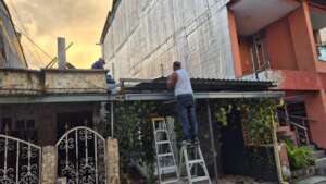 Replacing damaged tiles on Ana's roof.