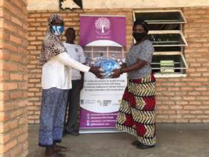 Ruth hands over masks to Hamela, the Headteacher