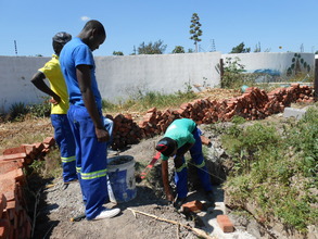 Foster showing the boys bricklaying 101!