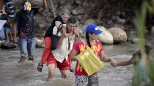 SAI Volunteer carries migrant woman on his back.
