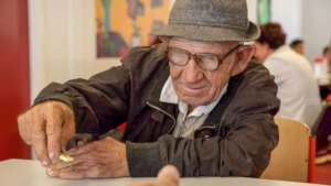 Qani playing dominos at the Amaro Tan soup kitchen