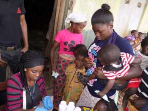 Volunteer giving vitamins to children and mother