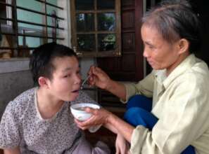Mrs Do feeds her bedridden daughter Luyen