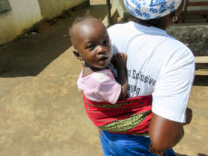A community health worker carries her baby