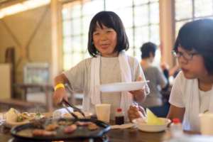 Child shares food during community meal