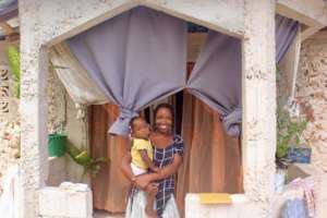 A participant stands in front of her new home.