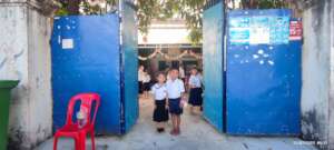 Two siblings are standing in front of the school