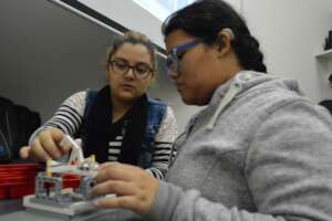 Young women beneficiaries working on their robot