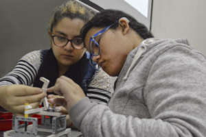 Two young deaf women learning robotics