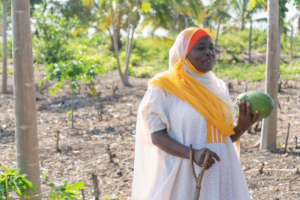 Latifah holds a papaya harvested from her orchard