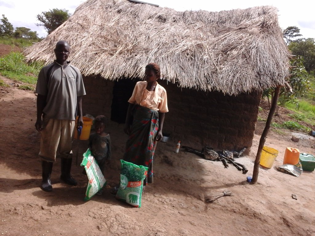 Mr. Songolo, wife, home w/straw roof