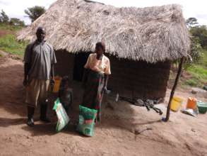 Mr. Songolo, wife, home w/straw roof
