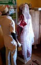 Health worker checking weight of a pregnant woman