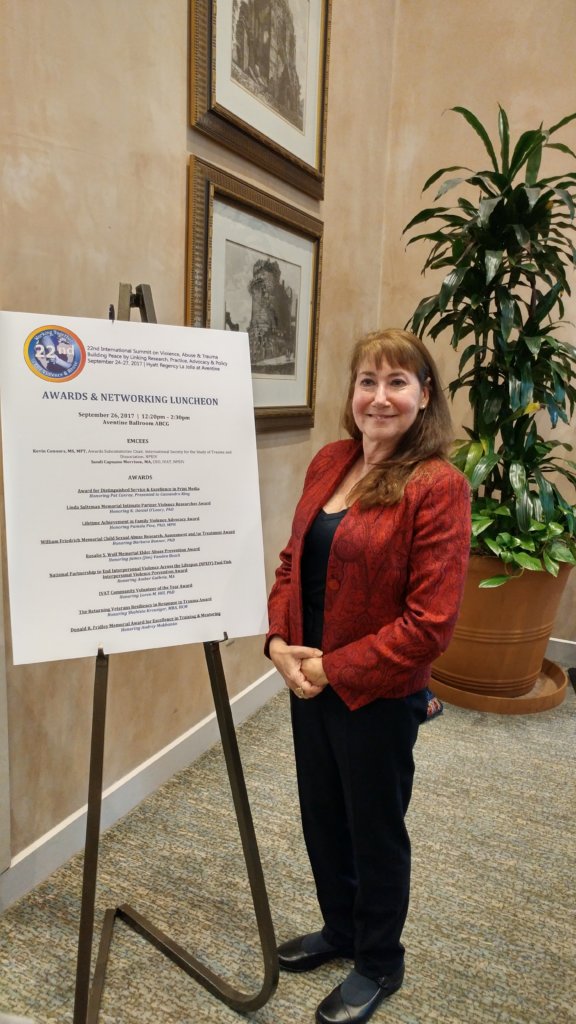 Pamela J Pine in front of IVAT Awards Poster