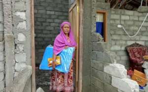Mas'ad in front of her home with an Oxfam tarp