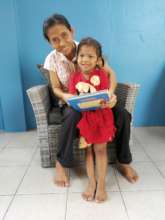 Our Nursery Teacher reads to a Kid in new chair