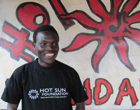 Reinhert in front of Hot Sun Foundation sign board