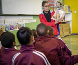 Youth reading a book to children in class
