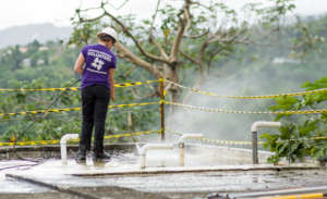 Volunteer Prepping a Damaged Roof for Sealant