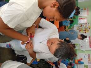 Fiordelis helping students make bracelets