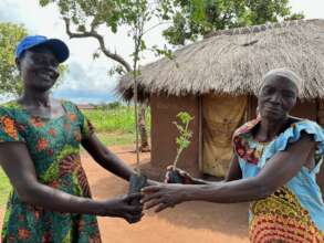 Beida presents a moringa to an elderly refugee