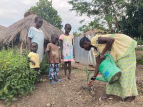 Children watch their mother plant a jackfruit tree