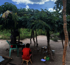 Young refugee repairs his radio under Senna bower