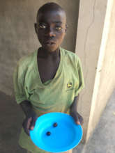 A boy shows two small wild fruits he collected